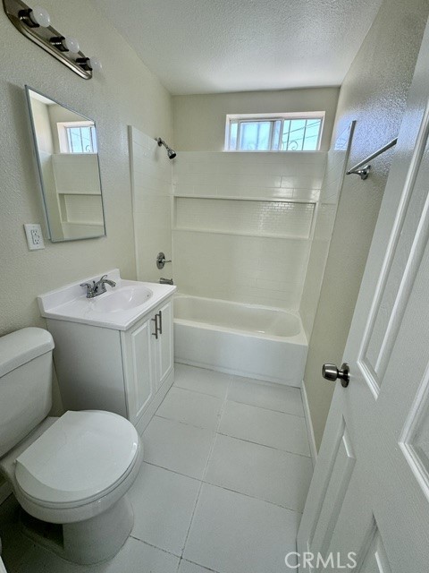 full bathroom with bathtub / shower combination, a textured ceiling, tile patterned floors, vanity, and toilet