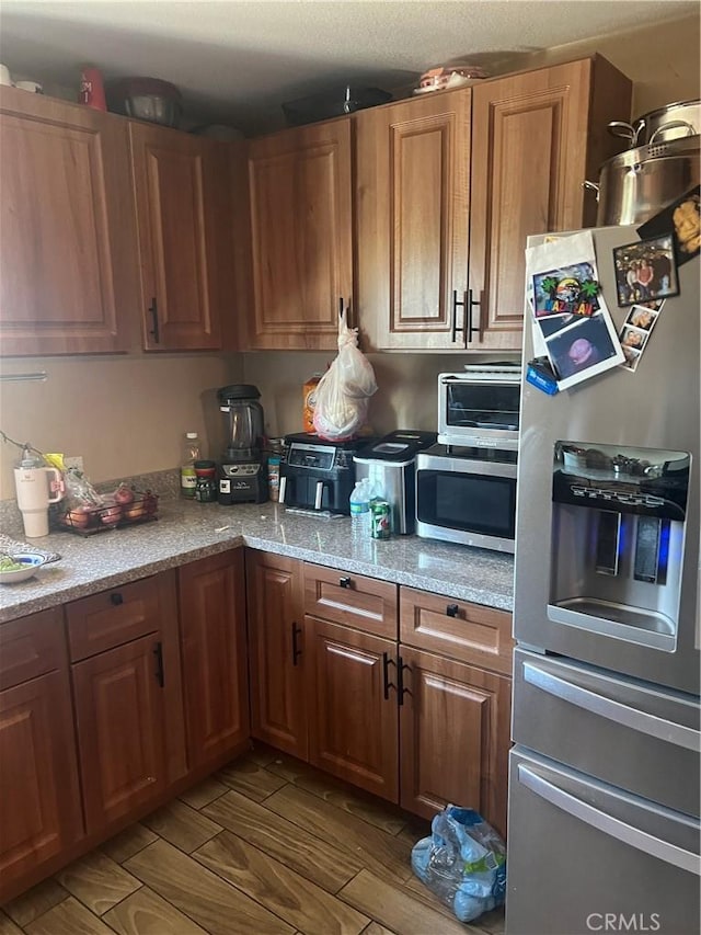 kitchen featuring light stone countertops, appliances with stainless steel finishes, and hardwood / wood-style flooring