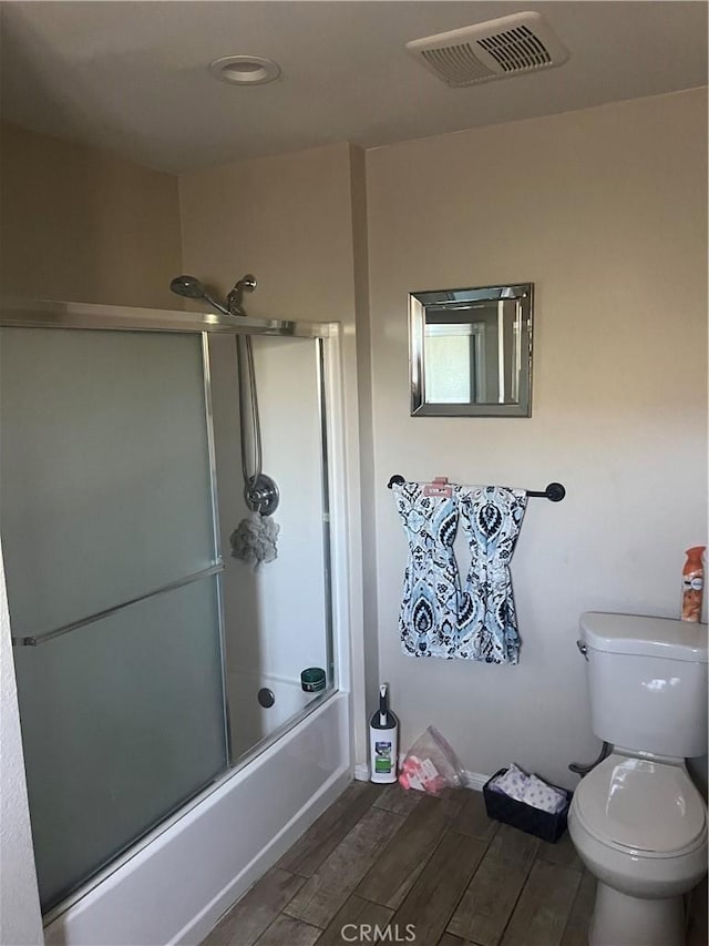 bathroom with toilet, bath / shower combo with glass door, and hardwood / wood-style flooring