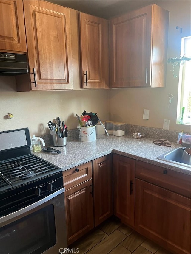 kitchen with light stone countertops, dark hardwood / wood-style flooring, extractor fan, sink, and black gas range