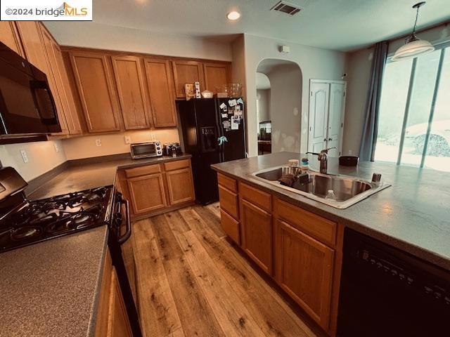 kitchen with sink, pendant lighting, black appliances, and light hardwood / wood-style flooring