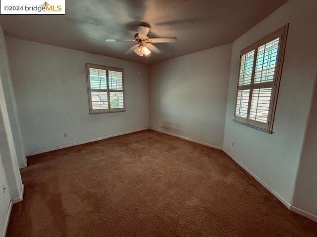 carpeted spare room with ceiling fan