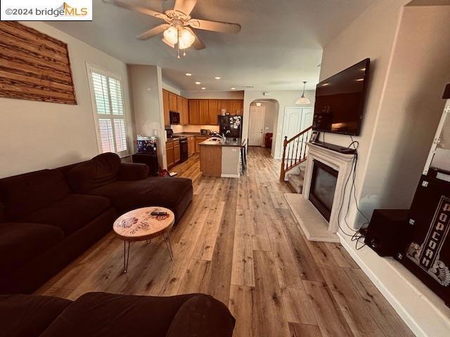 living room with light hardwood / wood-style floors, sink, a tile fireplace, and ceiling fan