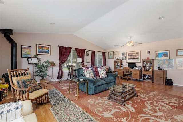 living room with ceiling fan, hardwood / wood-style floors, vaulted ceiling, and a wood stove