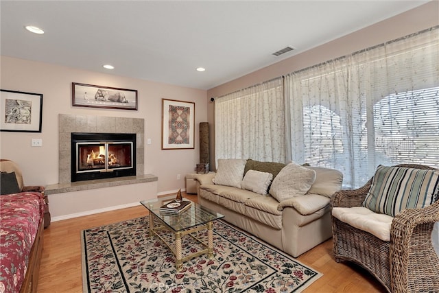 living room with light wood-type flooring and a tile fireplace