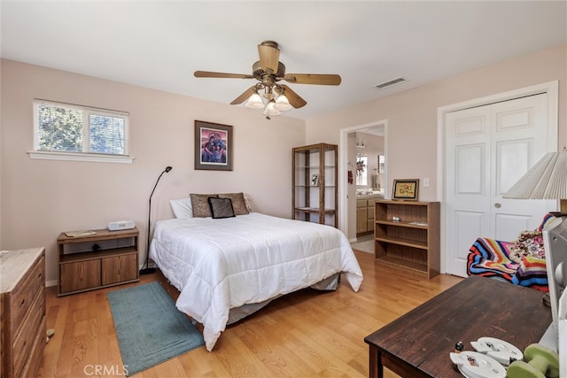 bedroom with a closet, connected bathroom, light hardwood / wood-style floors, and ceiling fan