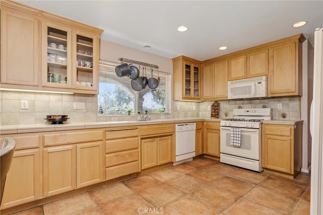 kitchen with light brown cabinets, tile countertops, backsplash, and white appliances