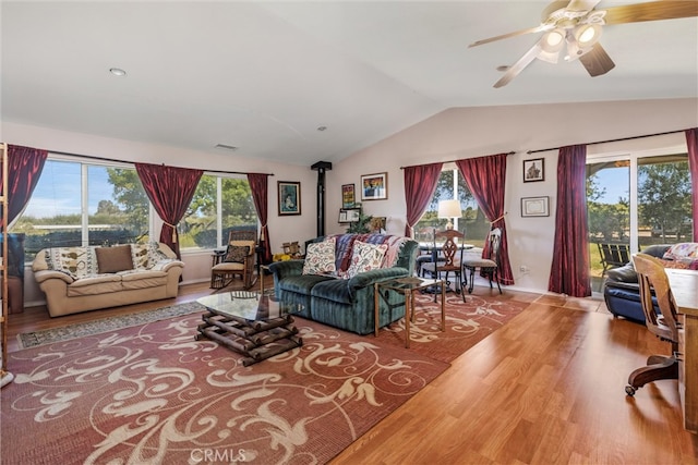 living room featuring a wood stove, vaulted ceiling, ceiling fan, and hardwood / wood-style floors