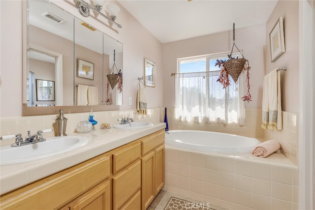 bathroom with vanity, a relaxing tiled tub, and tile patterned flooring