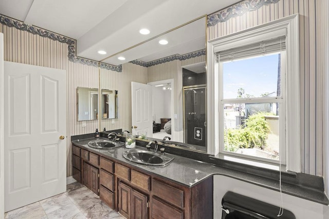 bathroom with vanity, a shower with shower door, and a wealth of natural light