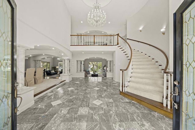 entrance foyer with a chandelier, a high ceiling, and decorative columns