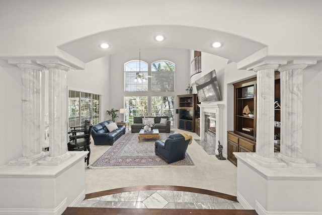 living room with a high ceiling, ornate columns, a fireplace, and ceiling fan