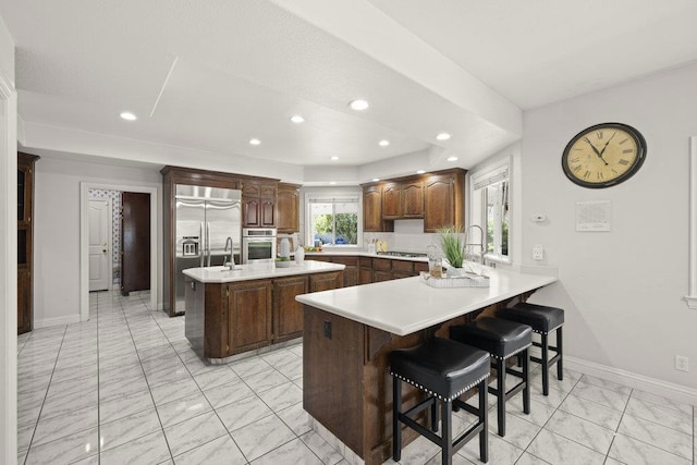 kitchen with a breakfast bar area, kitchen peninsula, sink, a center island, and appliances with stainless steel finishes