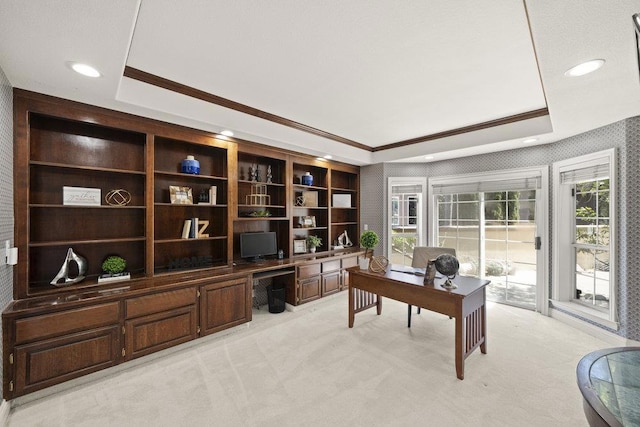 carpeted office featuring built in desk, crown molding, and a raised ceiling