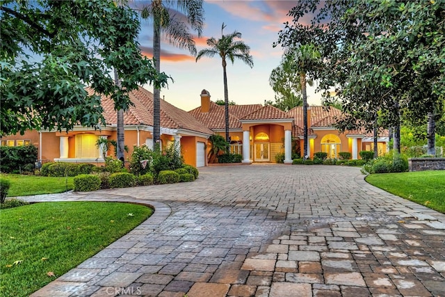 mediterranean / spanish-style home featuring a yard and a garage