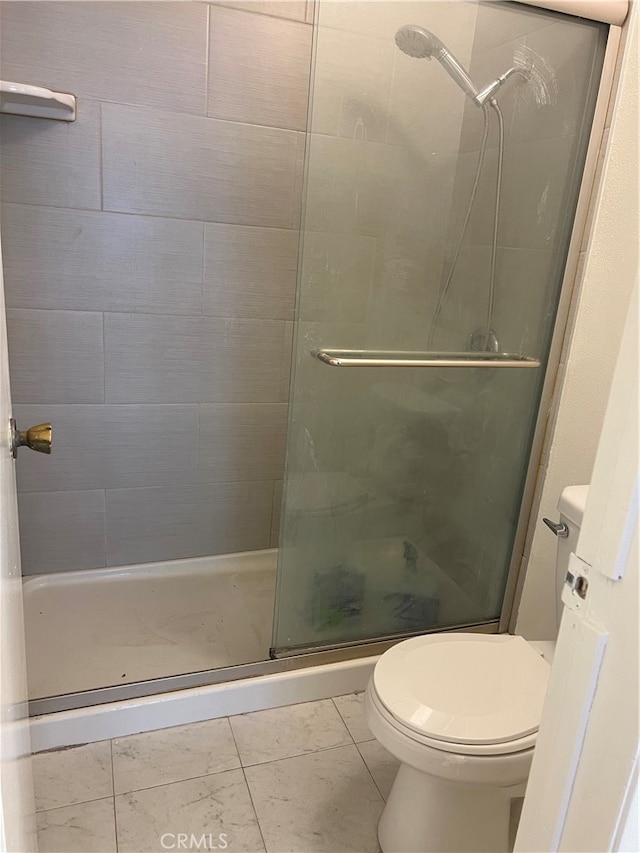 bathroom with a shower with door and toilet