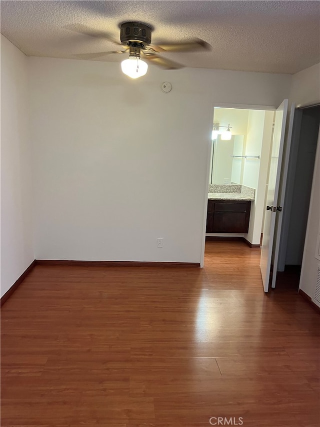 spare room with a textured ceiling, dark hardwood / wood-style floors, and ceiling fan