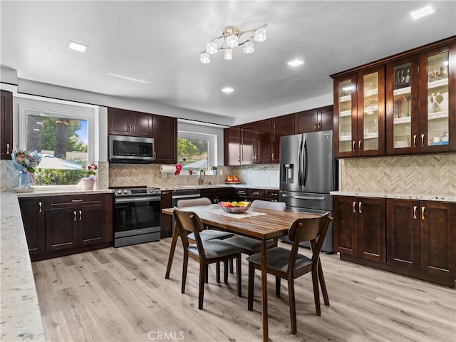 kitchen with appliances with stainless steel finishes, a wealth of natural light, and light wood-type flooring