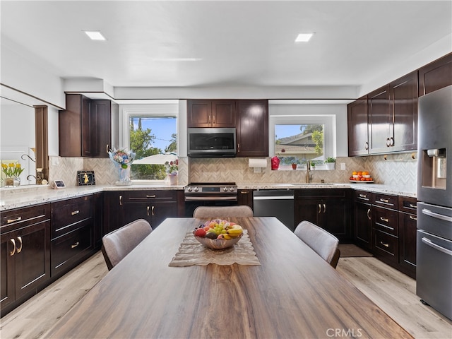 kitchen featuring backsplash, appliances with stainless steel finishes, dark brown cabinets, and light hardwood / wood-style floors