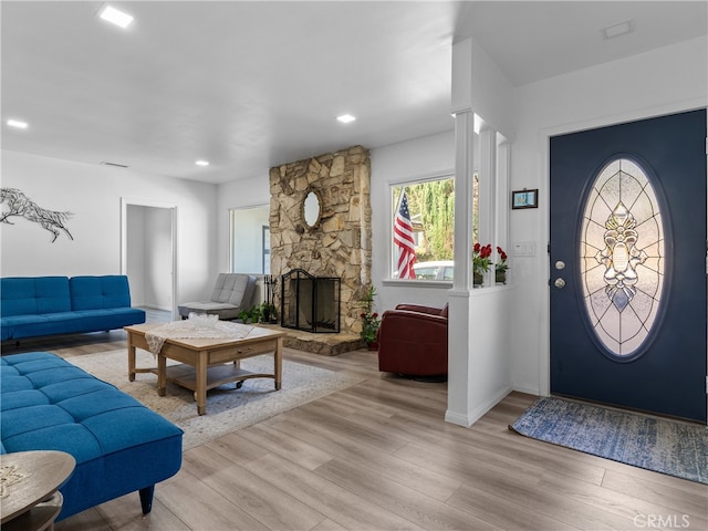 foyer with a stone fireplace and light wood-type flooring