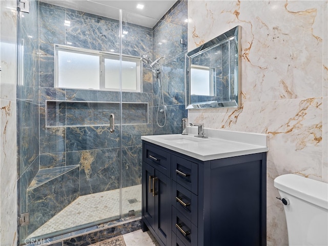 bathroom featuring toilet, a shower with shower door, vanity, and tile walls