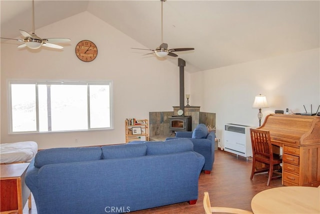 living room with dark hardwood / wood-style flooring, heating unit, ceiling fan, and a wood stove