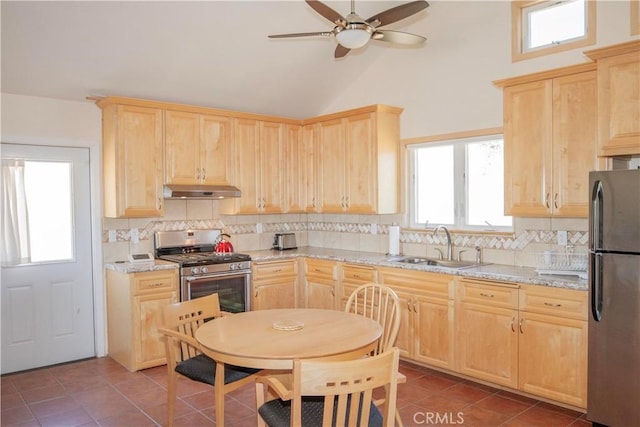 kitchen featuring light stone counters, stainless steel appliances, and light brown cabinetry