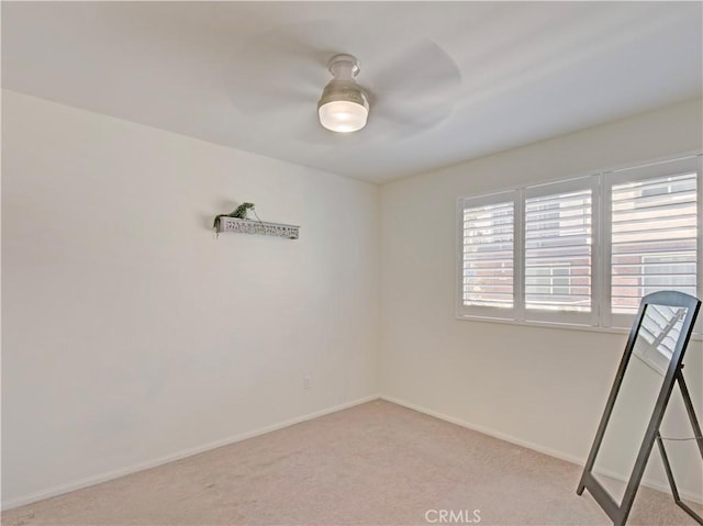 empty room featuring ceiling fan and light colored carpet