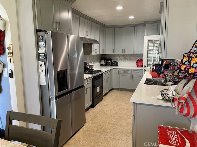 kitchen with stainless steel fridge, decorative backsplash, gray cabinets, black range with gas cooktop, and sink