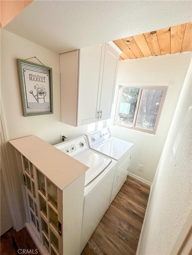 laundry area with a textured ceiling, washing machine and dryer, dark wood finished floors, cabinet space, and baseboards