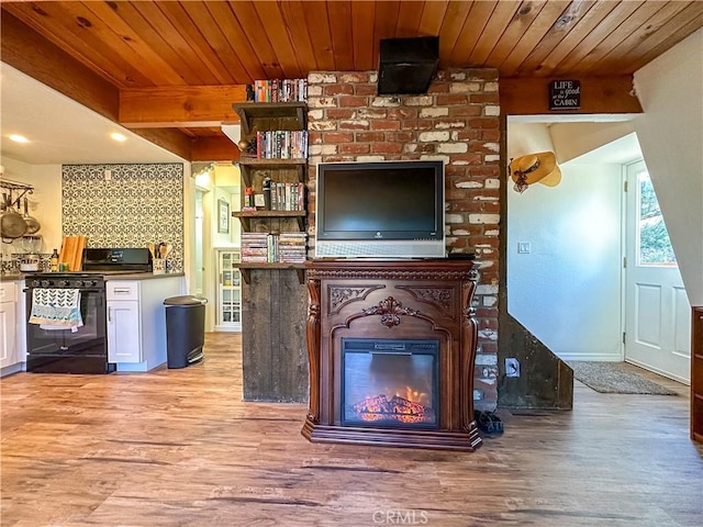 unfurnished living room featuring a glass covered fireplace, wooden ceiling, and light wood-style floors