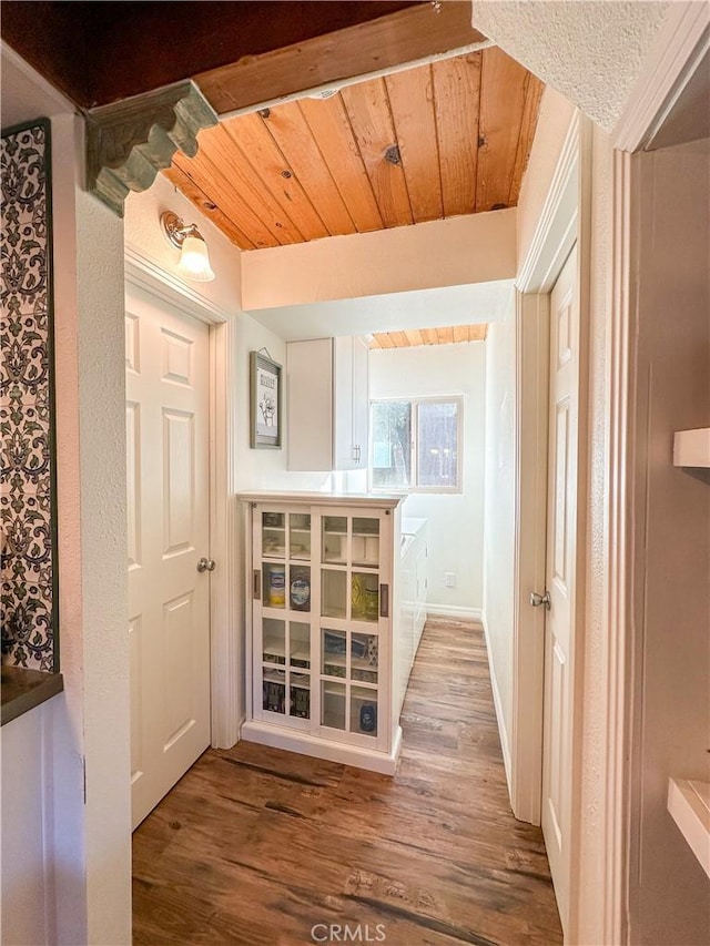 corridor featuring wood ceiling, baseboards, and wood finished floors