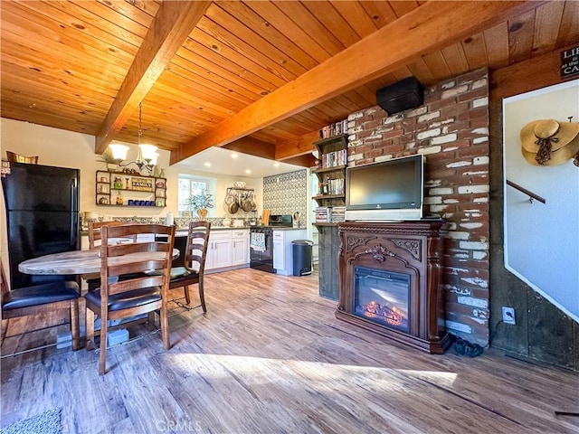 dining space featuring beam ceiling, a glass covered fireplace, light wood-style flooring, and wooden ceiling