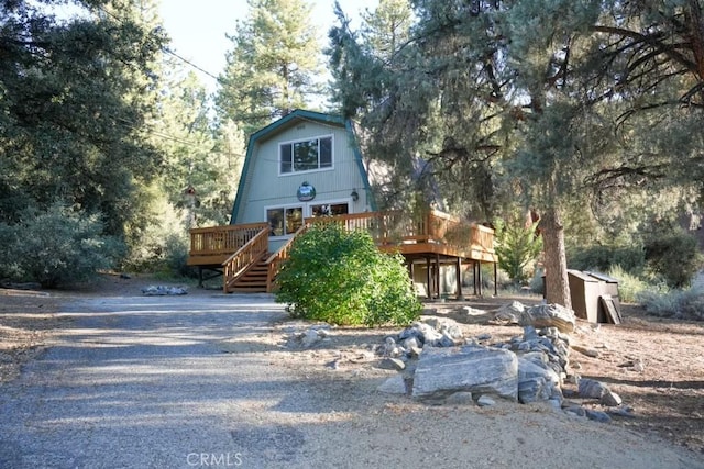 a-frame style home with a gambrel roof and a wooden deck