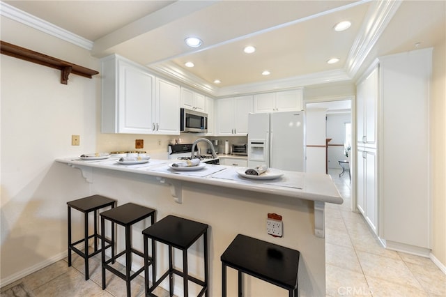 kitchen with stainless steel appliances, white cabinets, kitchen peninsula, and a breakfast bar area