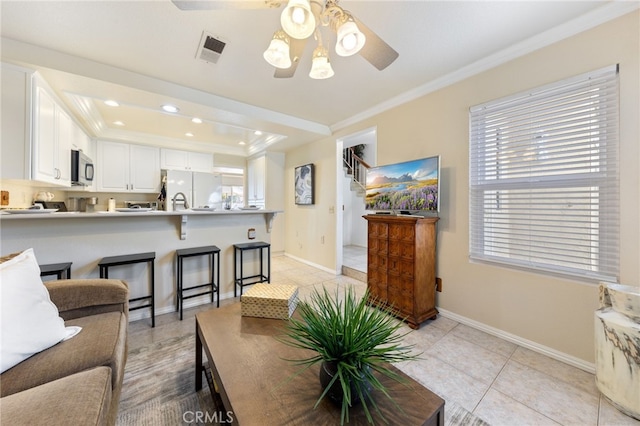 tiled living room with ornamental molding and ceiling fan