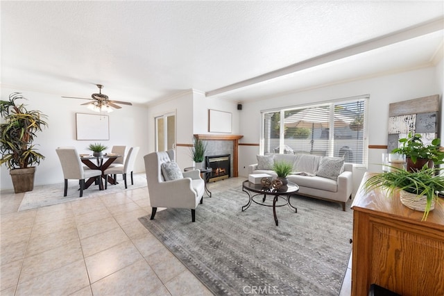 living room with a tiled fireplace, ceiling fan, light tile patterned floors, and a textured ceiling