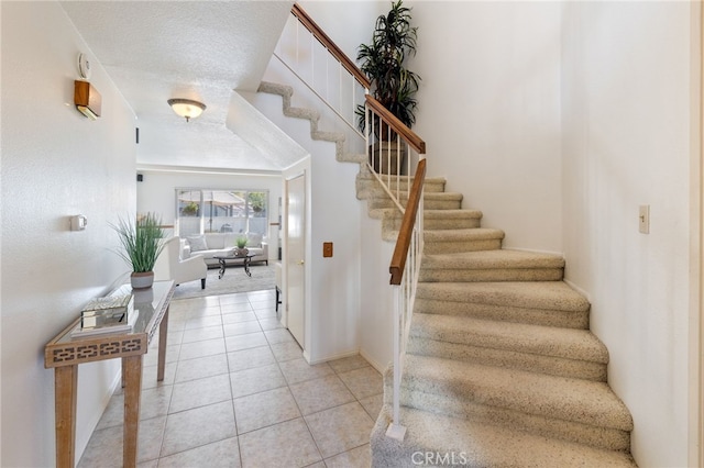 staircase with a textured ceiling and tile patterned flooring