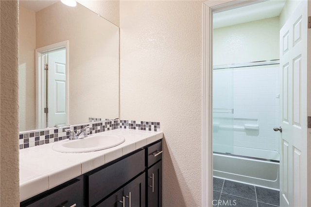 bathroom featuring tile patterned flooring, backsplash, vanity, and enclosed tub / shower combo