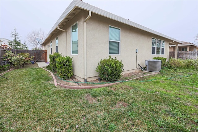 view of side of property featuring central AC unit and a lawn