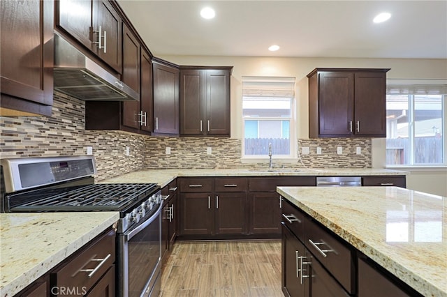 kitchen with stainless steel appliances, sink, dark brown cabinetry, and light hardwood / wood-style floors