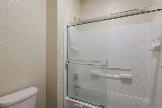 bathroom featuring enclosed tub / shower combo and toilet