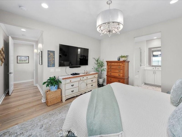 bedroom with connected bathroom, sink, a chandelier, and light hardwood / wood-style floors