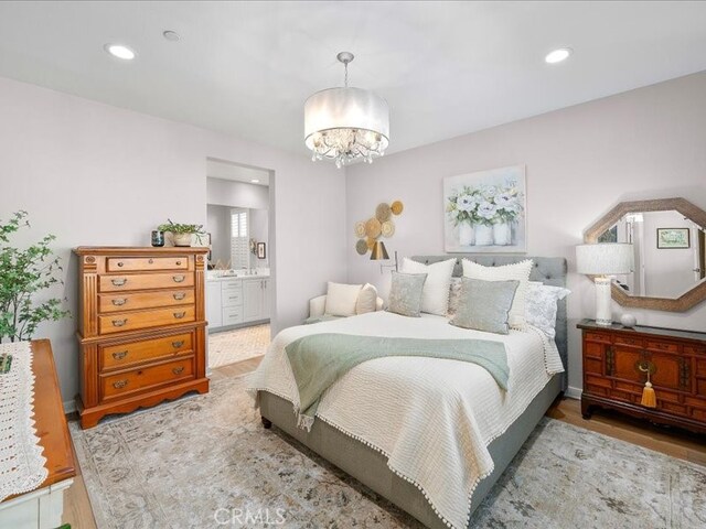 bedroom with ensuite bath, light hardwood / wood-style flooring, and a chandelier