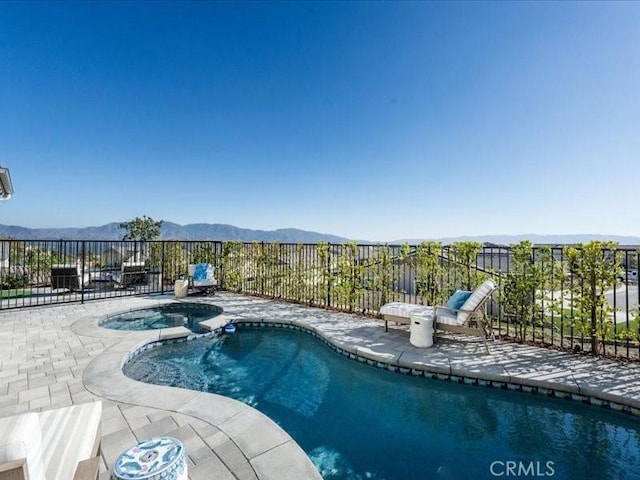 view of pool with an in ground hot tub, a mountain view, and a patio