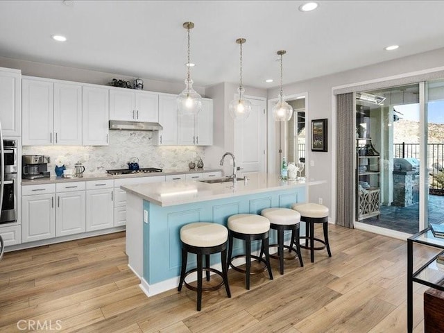 kitchen featuring white cabinetry, sink, and an island with sink