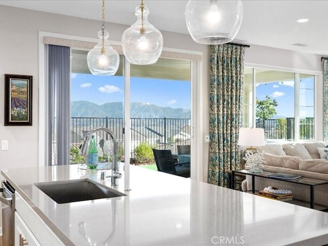 kitchen with decorative light fixtures, a mountain view, sink, and dishwasher