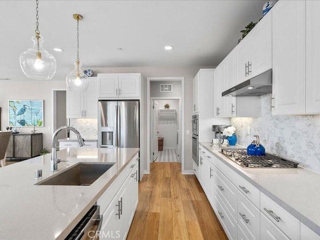 kitchen featuring sink, white cabinetry, hanging light fixtures, light wood-type flooring, and appliances with stainless steel finishes