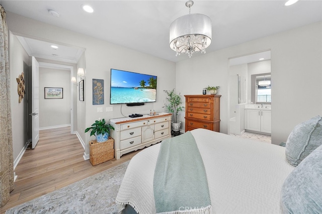 bedroom featuring ensuite bath, a chandelier, sink, and light hardwood / wood-style flooring