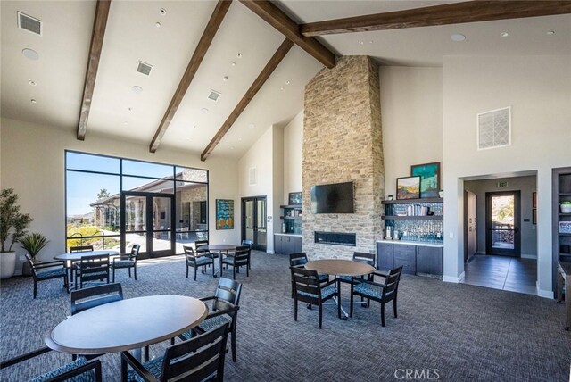 dining area with a fireplace, high vaulted ceiling, beam ceiling, and dark colored carpet